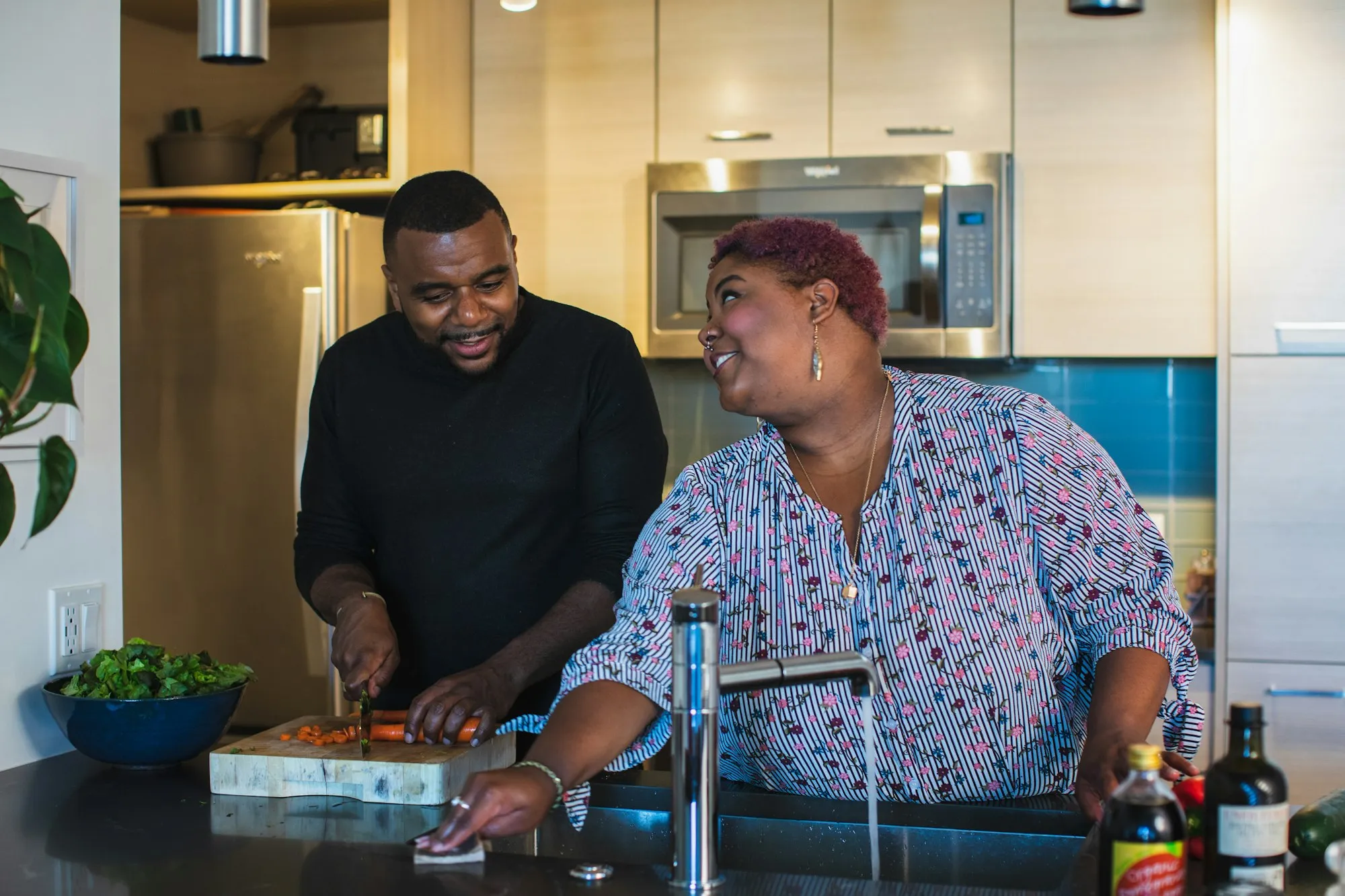 A mother and her adult son cooking together in a home kitchen