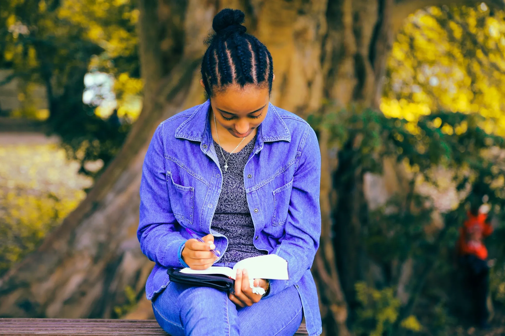 A young woman reading and taking notes outdoors