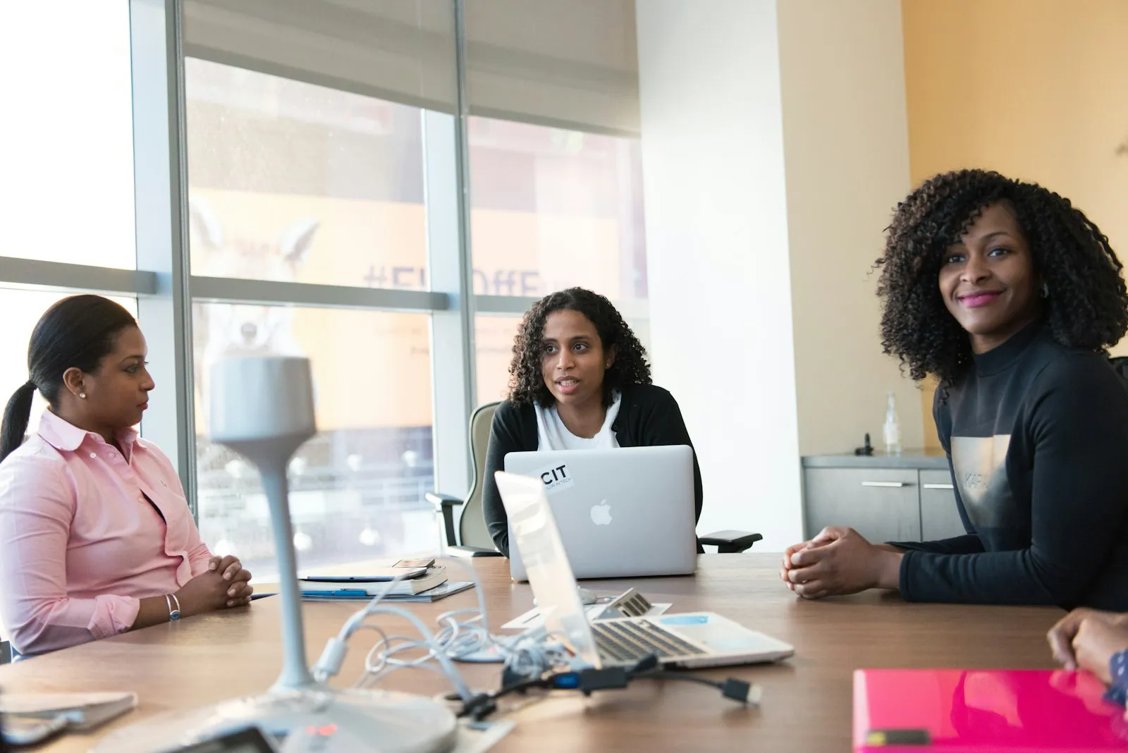 Three women working together at a table with laptops