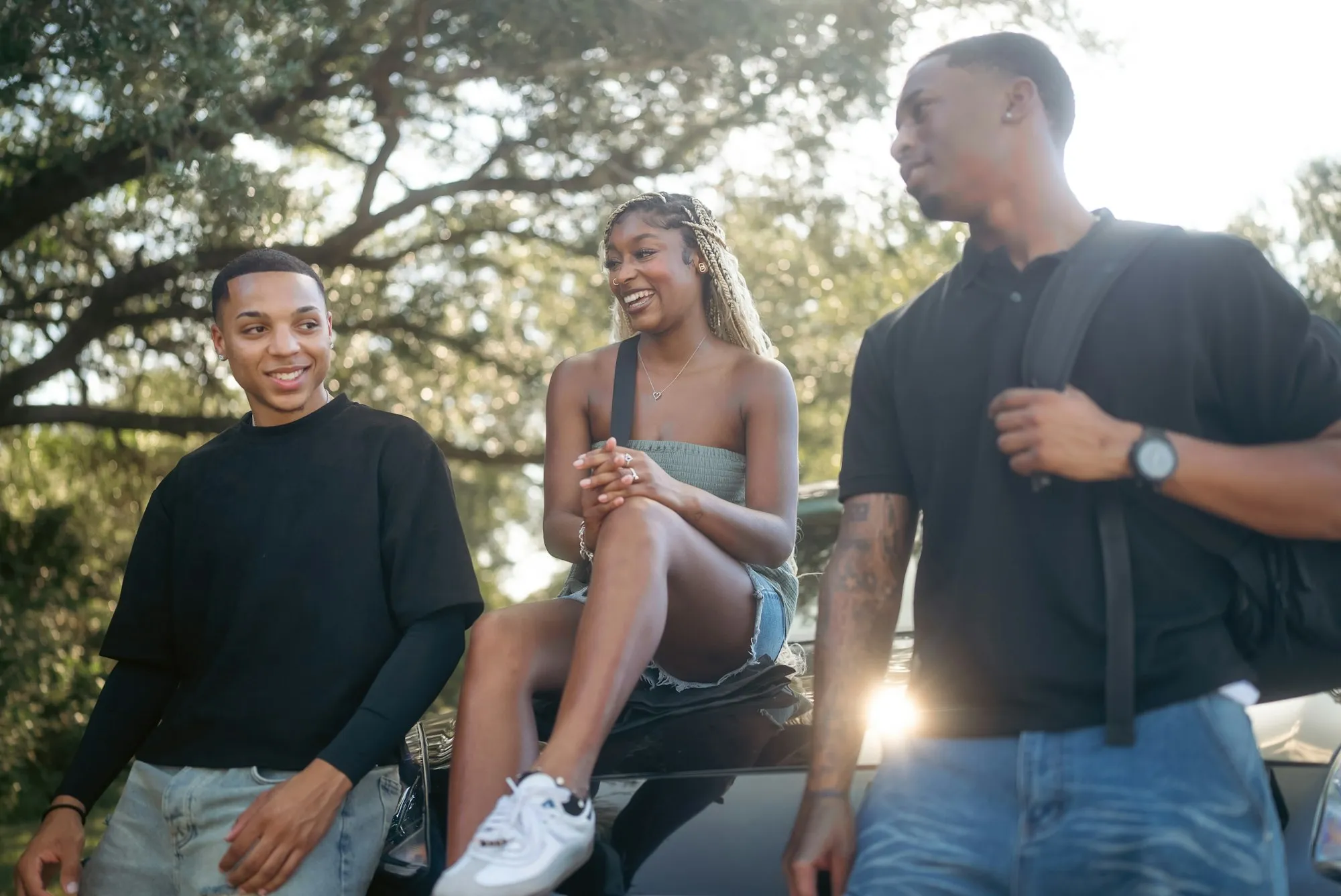 Three young adults talking together outdoors on a sunny day